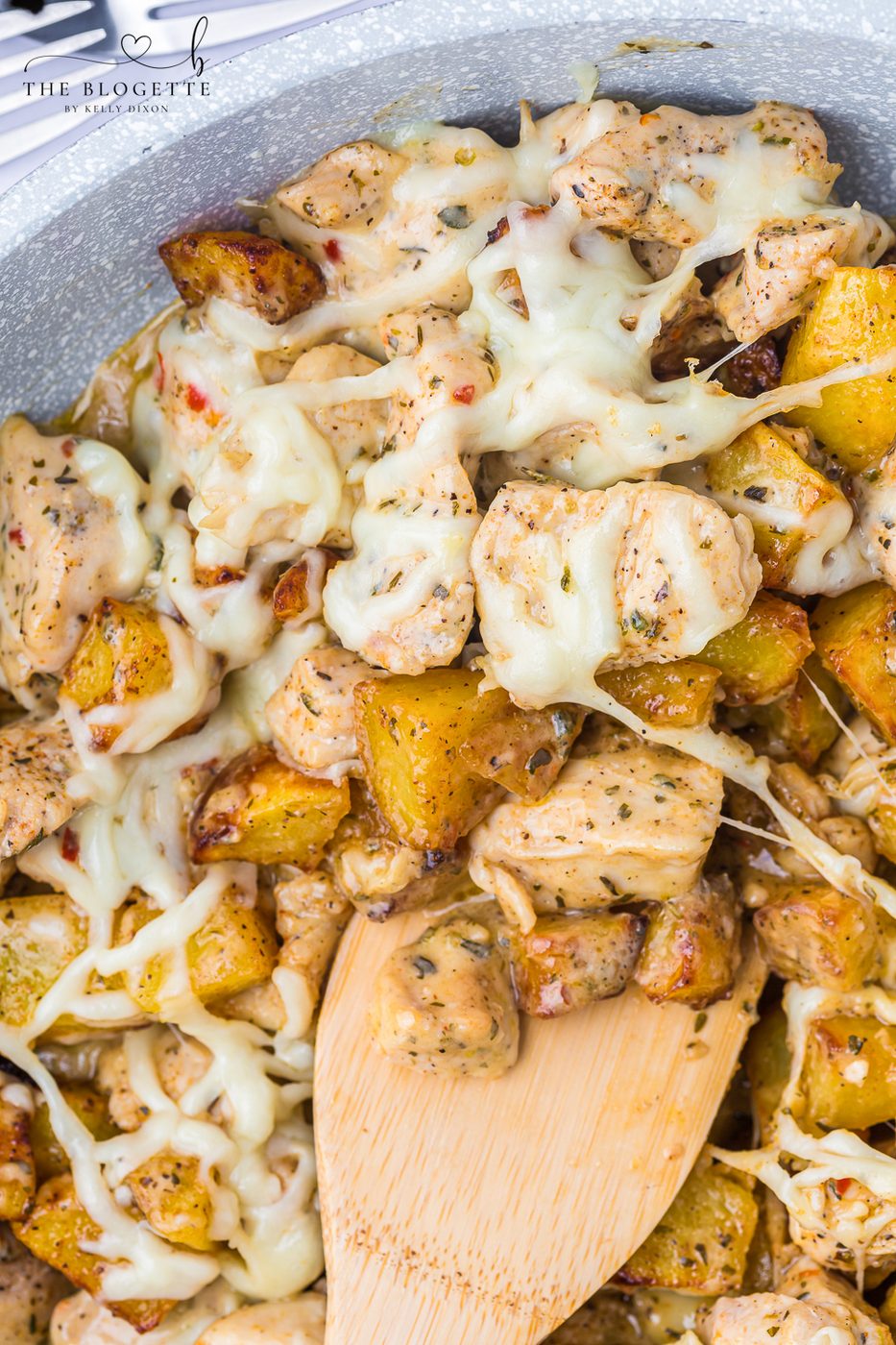 Garlic Parmesan Chicken and Potatoes recipe! A skillet with potatoes and chicken in a buttery, garlic, Parmesan sauce, topped with cheese.