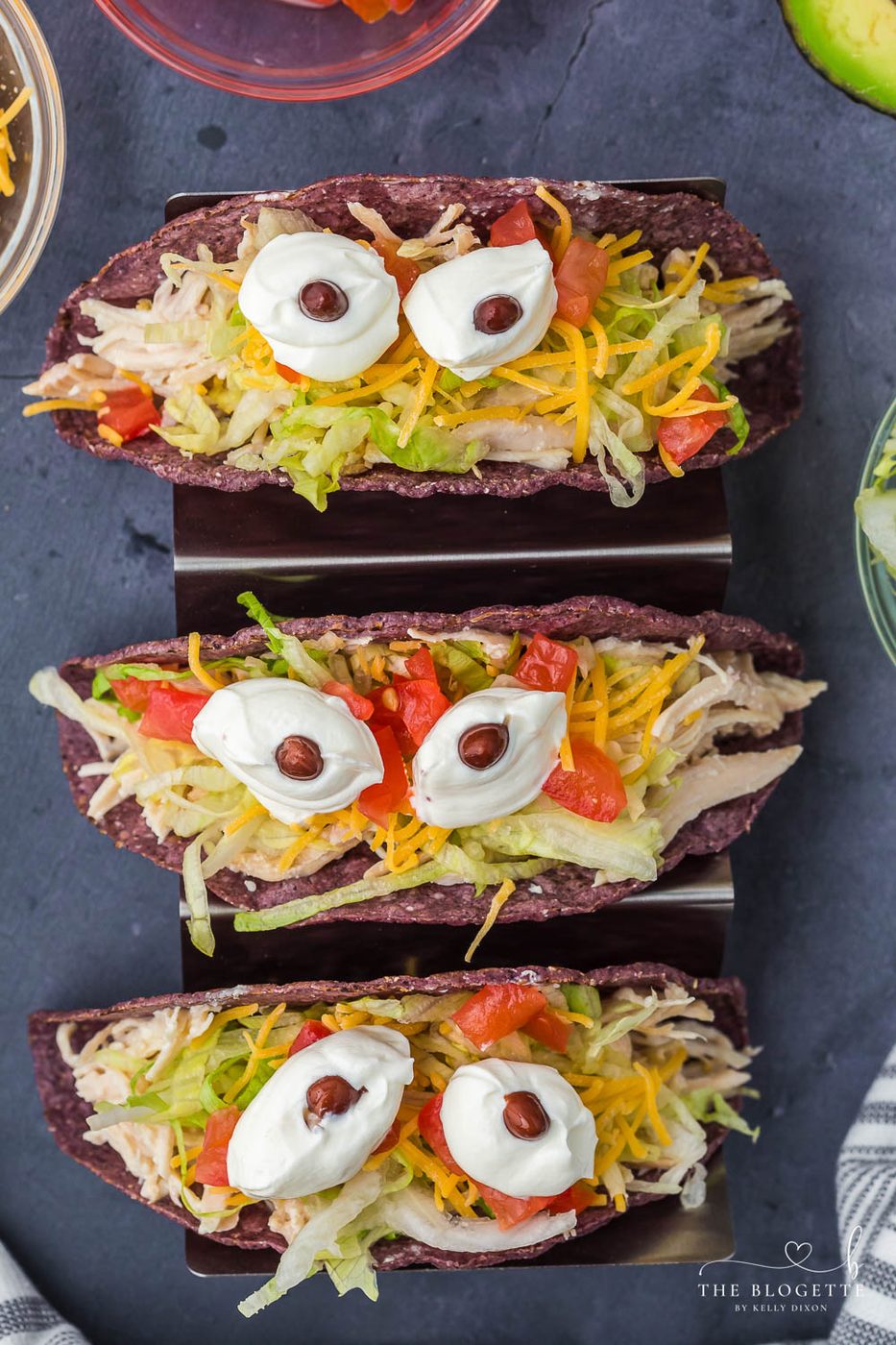 Monster Tacos for Halloween! These slow-cooker ranch chicken tacos feature blue corn taco shells and spooky sour cream eyes!