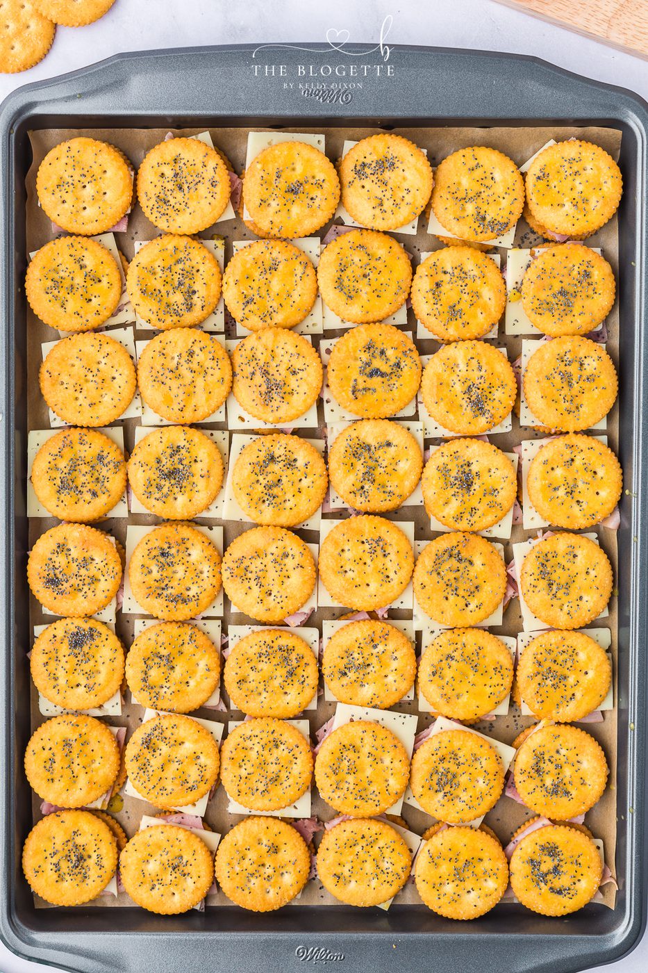 Brush the tops of the sandwiches with the melted butter mixture and then sprinkle a pinch of poppy seeds over each sandwich.