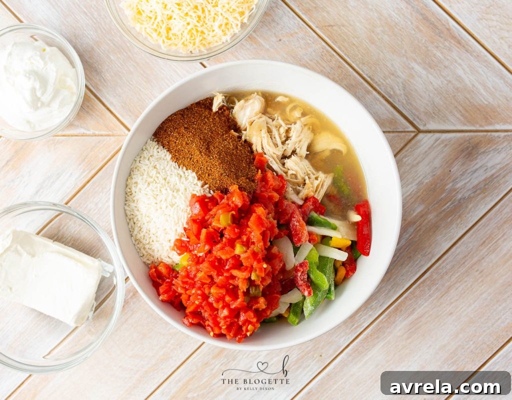 Zesty Chicken Fajita Bake 4 A selection of ingredients laid out on a kitchen counter, including shredded chicken, instant rice, cream cheese, sour cream, frozen vegetables, diced tomatoes, chicken broth, fajita seasoning, and shredded Mexican cheese.