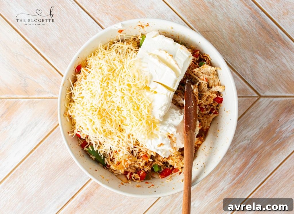 Zesty Chicken Fajita Bake 5 A large mixing bowl containing shredded chicken, rice, vegetables, and seasonings, with creamy ingredients like cream cheese and sour cream being added and stirred.