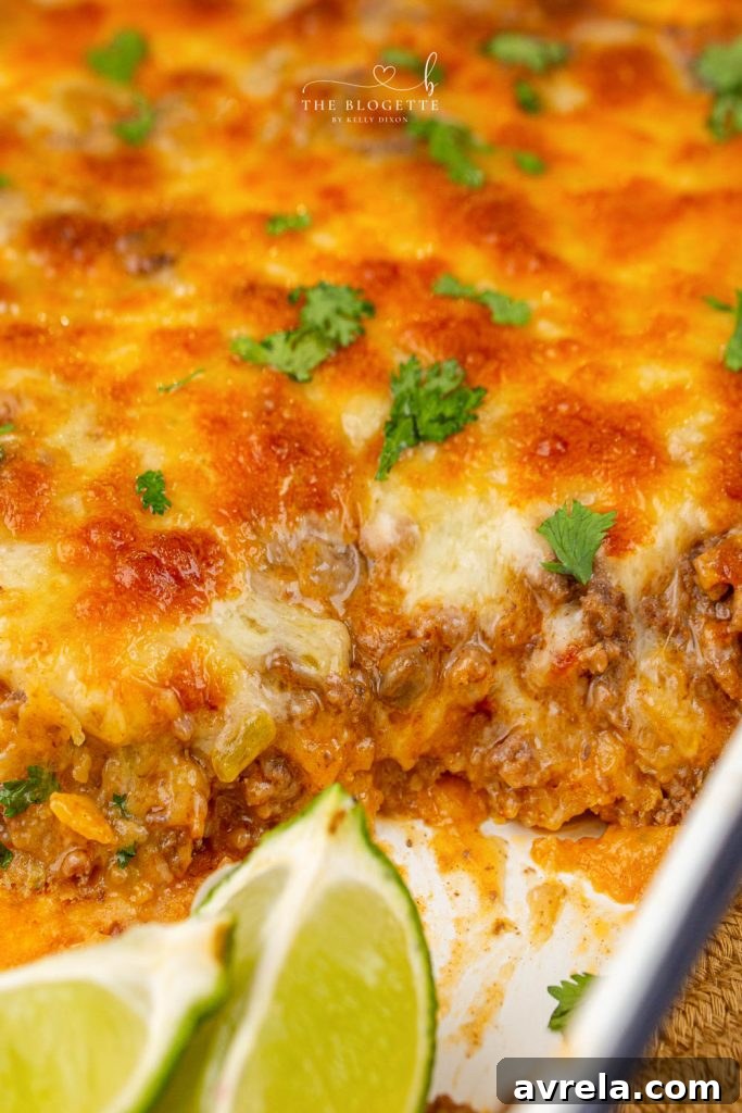 Ultimate Taco Bake 6 Cheesy Beef Taco Casserole with a spoonful taken out, showing layers