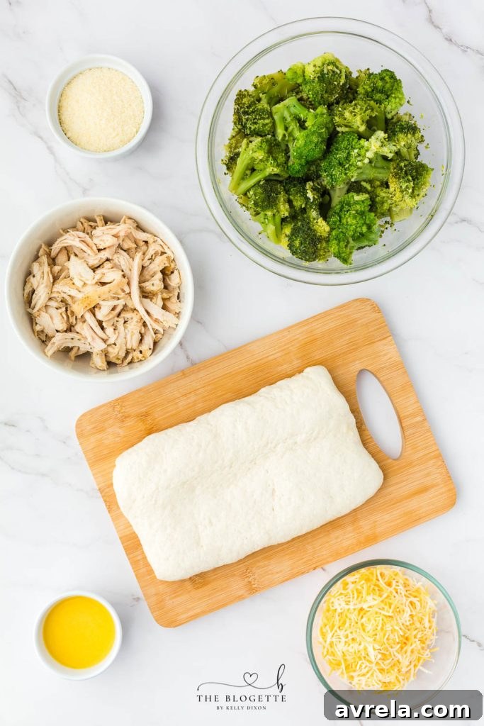 A spread of fresh ingredients including pizza dough, broccoli, cheese, and cooked chicken, ready for the ring recipe.