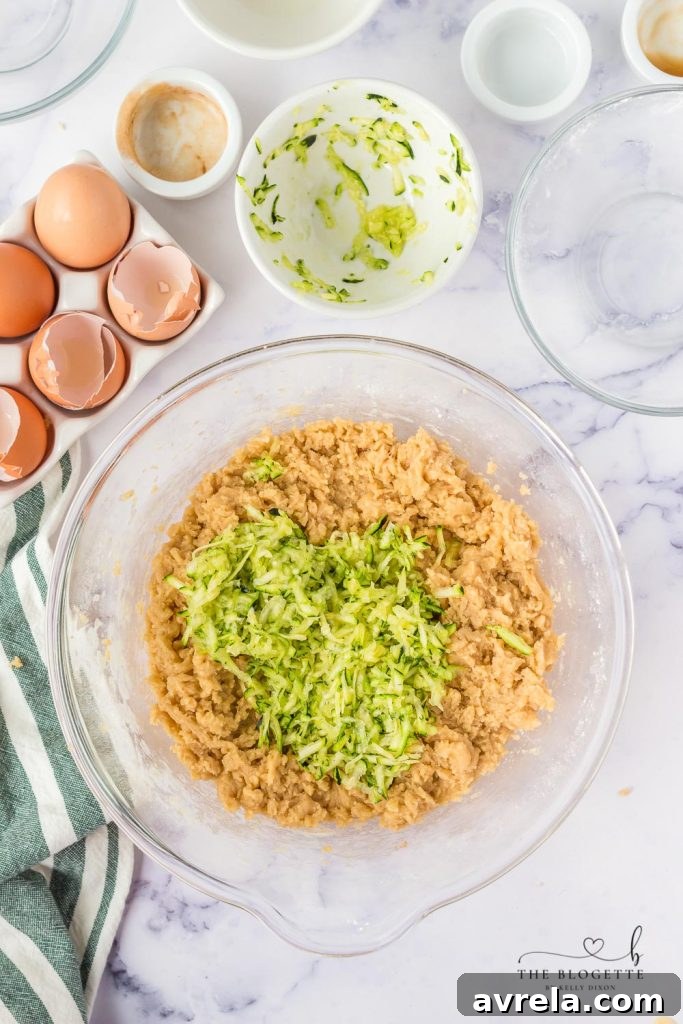 Shredded zucchini being squeezed of excess moisture with a paper towel, a critical step for perfect zucchini bread.