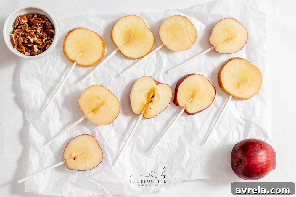 Freshly sliced apples with lollipop sticks inserted, ready for dipping.