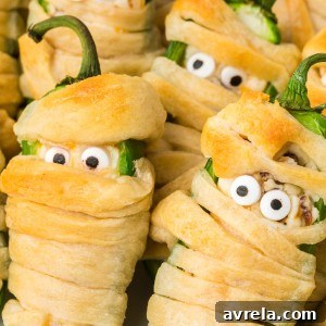Halloween Jalapeño Popper Mummies are adorably spooky jalapeños, filled with a cream cheese mixture, wrapped in crescent dough, and baked!