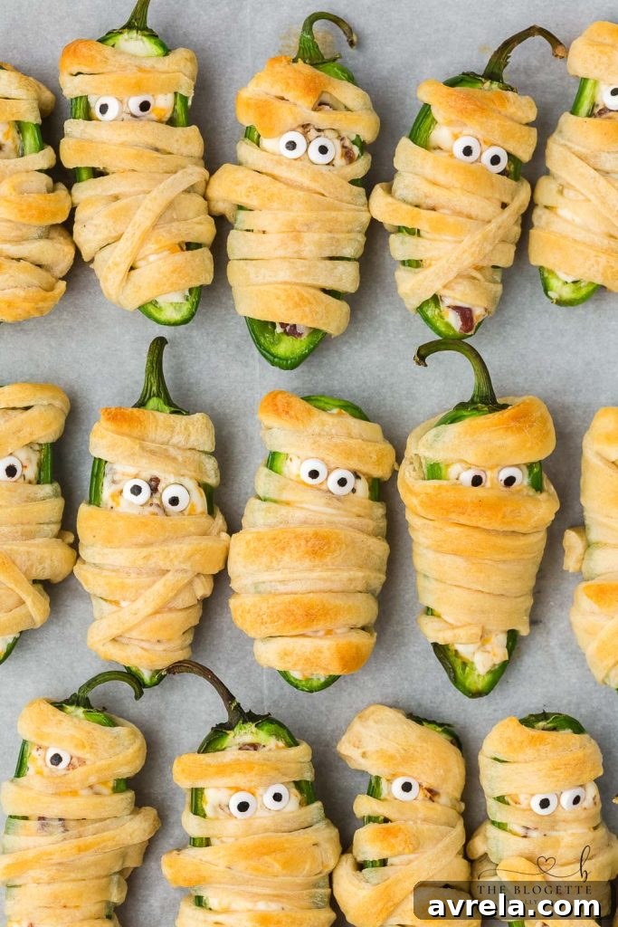 Halloween Jalapeño Popper Mummies are adorably spooky jalapeños, filled with a cream cheese mixture, wrapped in crescent dough, and baked to golden perfection.
