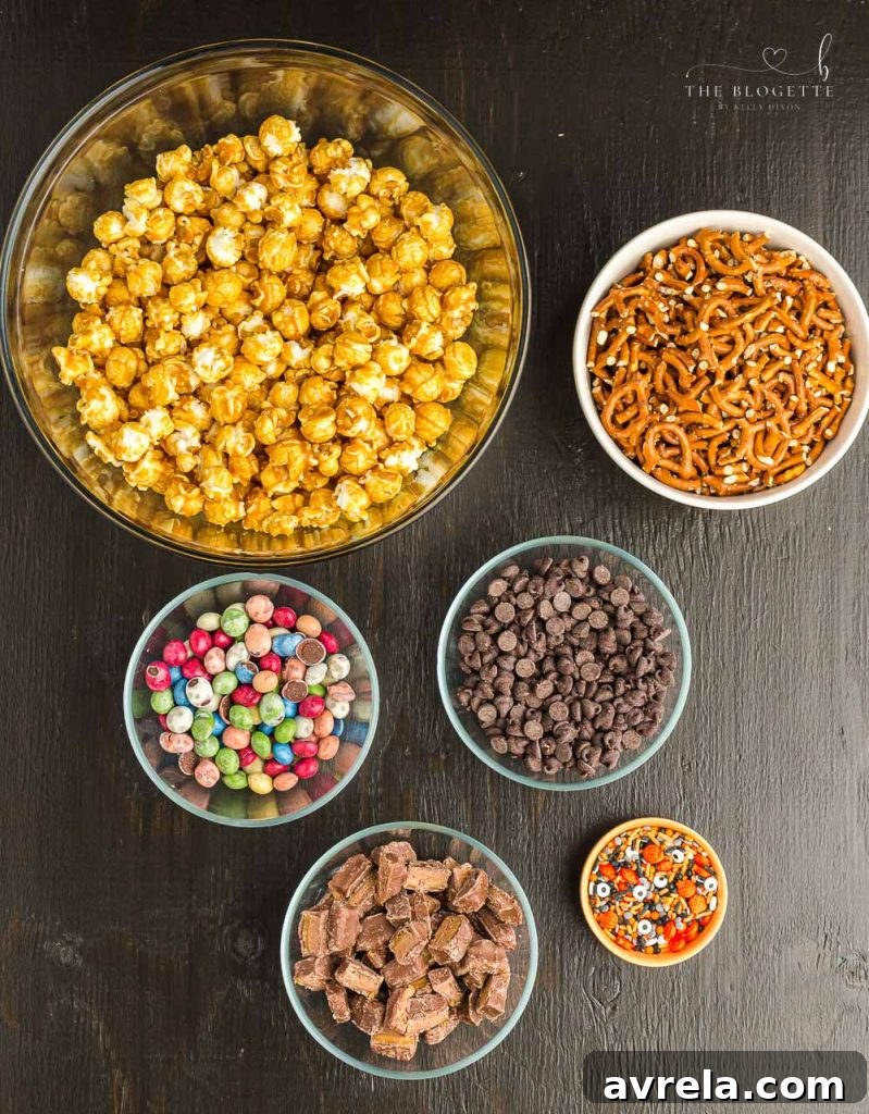 Fright Night Fuel 3 A flat lay image showcasing the individual ingredients for a delicious Halloween snack mix, including caramel popcorn, pretzels, chocolate chips, and various Halloween candies.