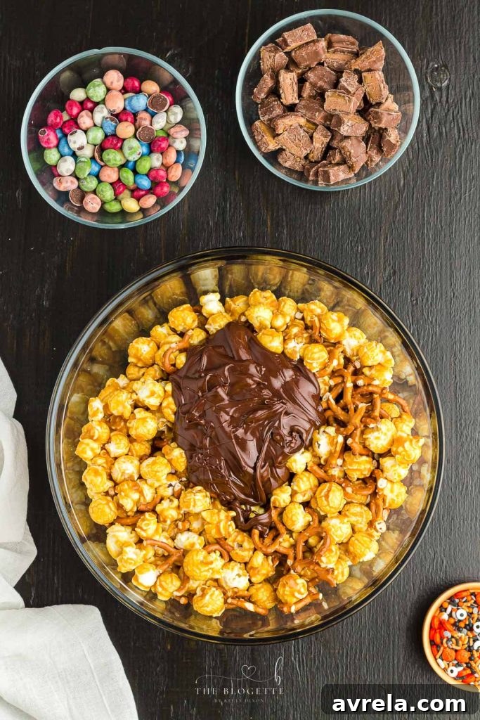 Fright Night Fuel 5 A large bowl filled with caramel popcorn and broken pretzels, coated in melted chocolate, ready for additional toppings.
