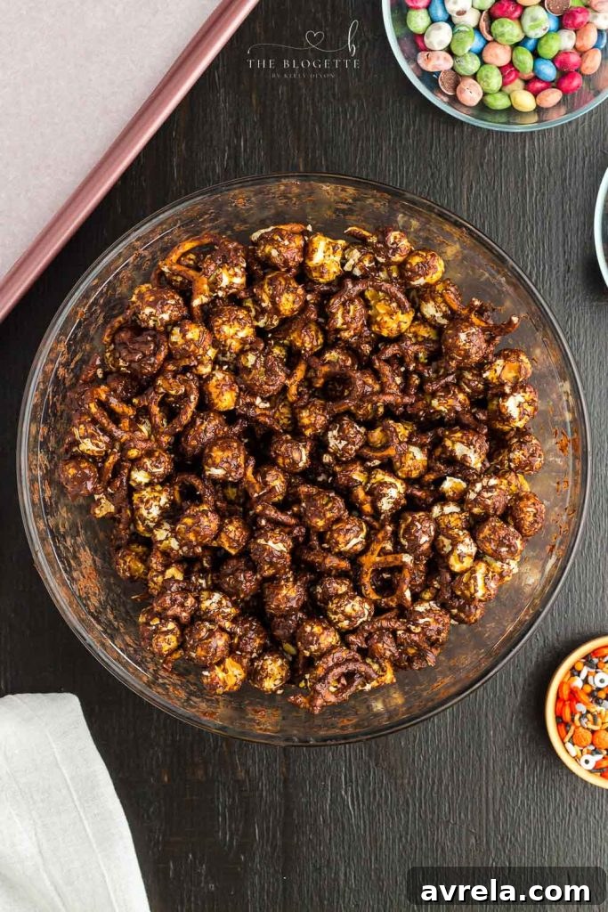 Fright Night Fuel 6 Close-up of caramel popcorn and pretzels being thoroughly mixed with melted chocolate in a large bowl.