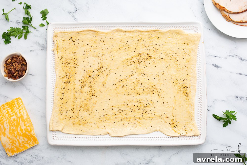 Garlic butter glaze being brushed onto crescent rolls before filling.