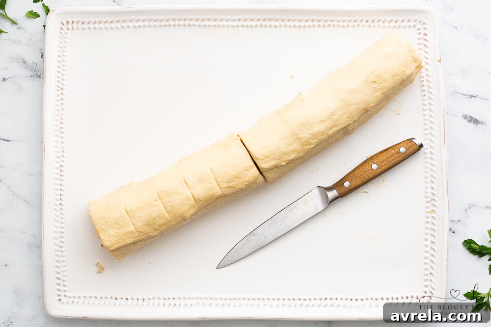 Cutting the rolled-up crescent dough into individual rounds.