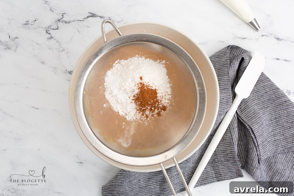 Sifting dry ingredients into a bowl, a crucial step for lump-free pumpkin pie cupcake batter.