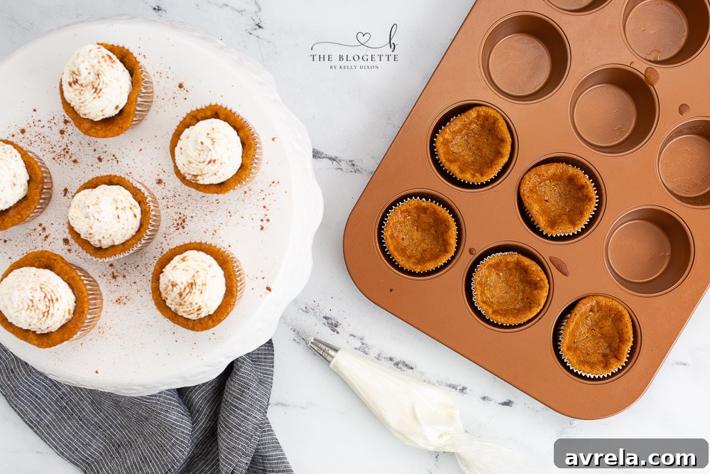 Adding a generous swirl of whipped cream to cooled Pumpkin Pie Cupcakes, enhancing their festive appeal.