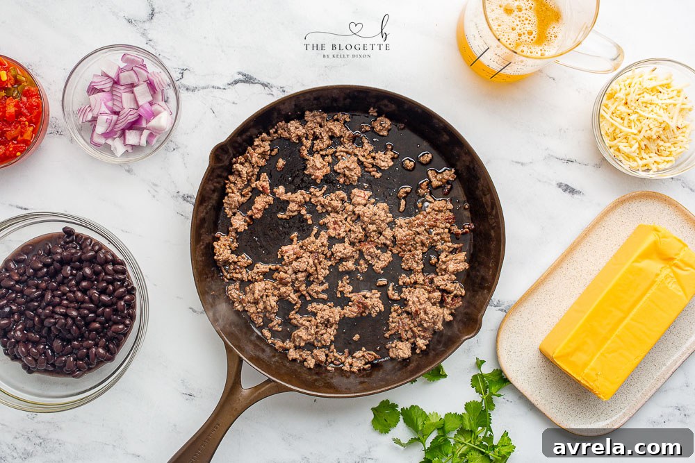Lean ground beef browning in a skillet, the first step to a delicious loaded queso dip.