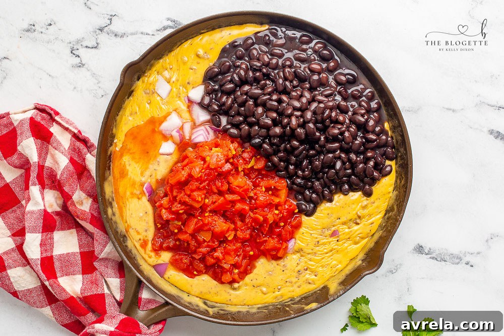 Another view of the loaded queso dip in the skillet, showcasing its texture and rich ingredients.
