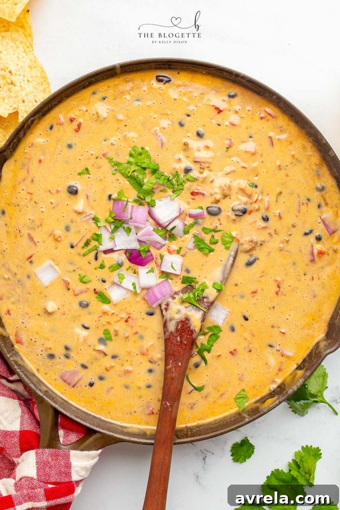 A large bowl of Loaded Queso Dip surrounded by tortilla chips, ready for a party.