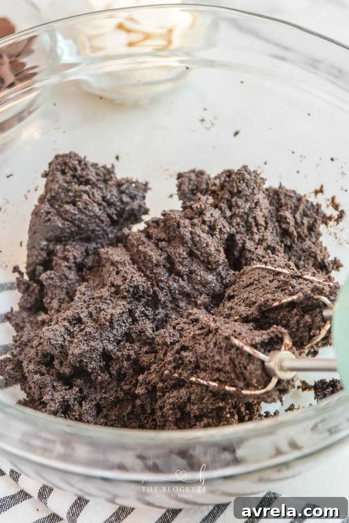 Step-by-step image showing how to mix the crushed Oreos, cream cheese, and vanilla extract for Oreo Truffles.