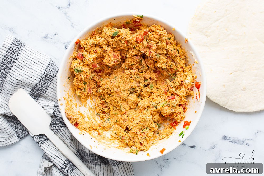 A close-up shot of the cheesy chicken mixture in a large bowl, perfectly blended and ready for spreading onto tortillas.