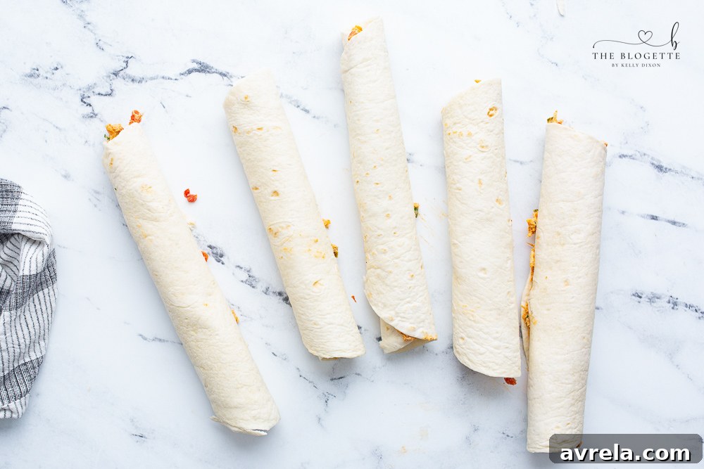 A perfectly rolled tortilla filled with chicken enchilada mixture, showcasing the technique for tight rolling before chilling and slicing.
