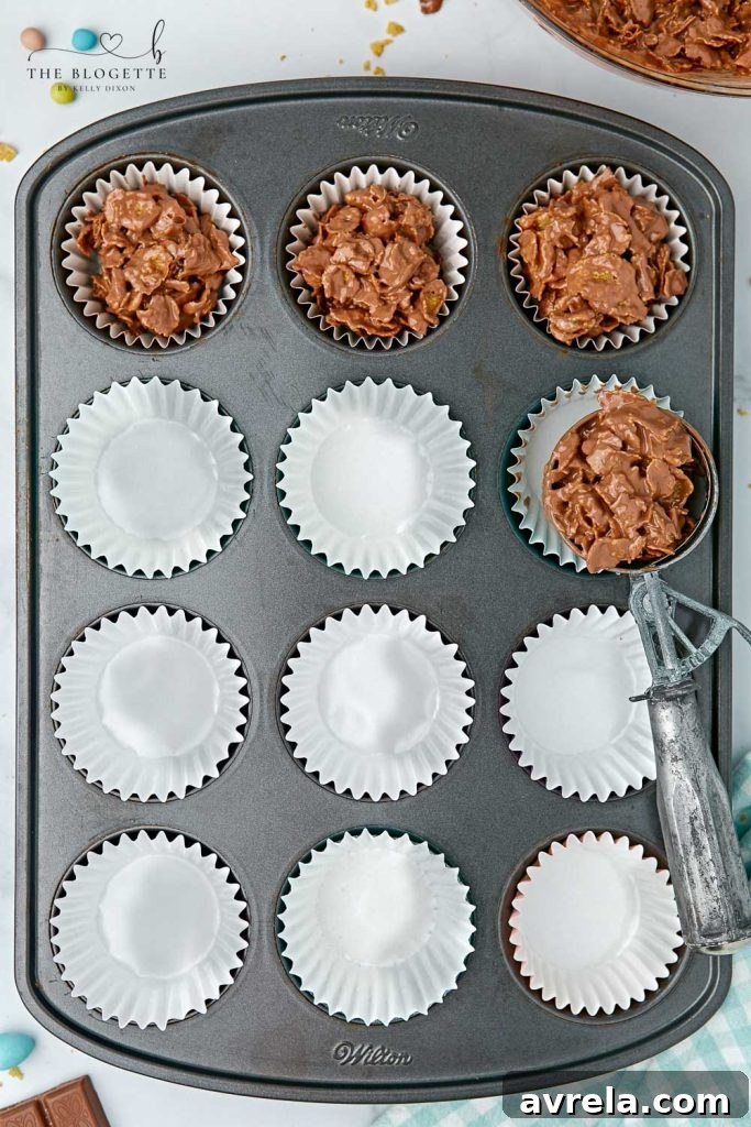 Chocolate covered cornflakes in cupcake liners with mini eggs, chilling in a muffin pan.