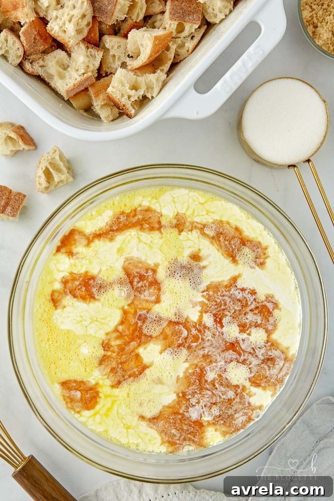 Morning Glory French Toast Bake 6 The rich cinnamon-cream mixture being poured over bread cubes in a baking dish.