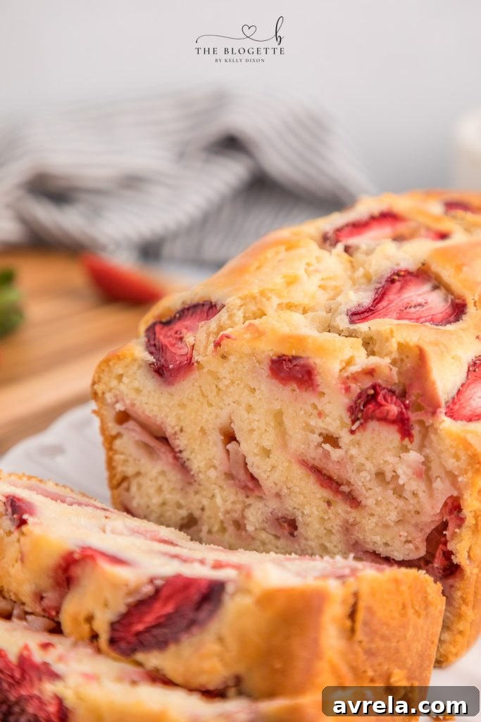 Close-up of a slice of Strawberry Bread, showing its tender crumb and pieces of fresh strawberry.