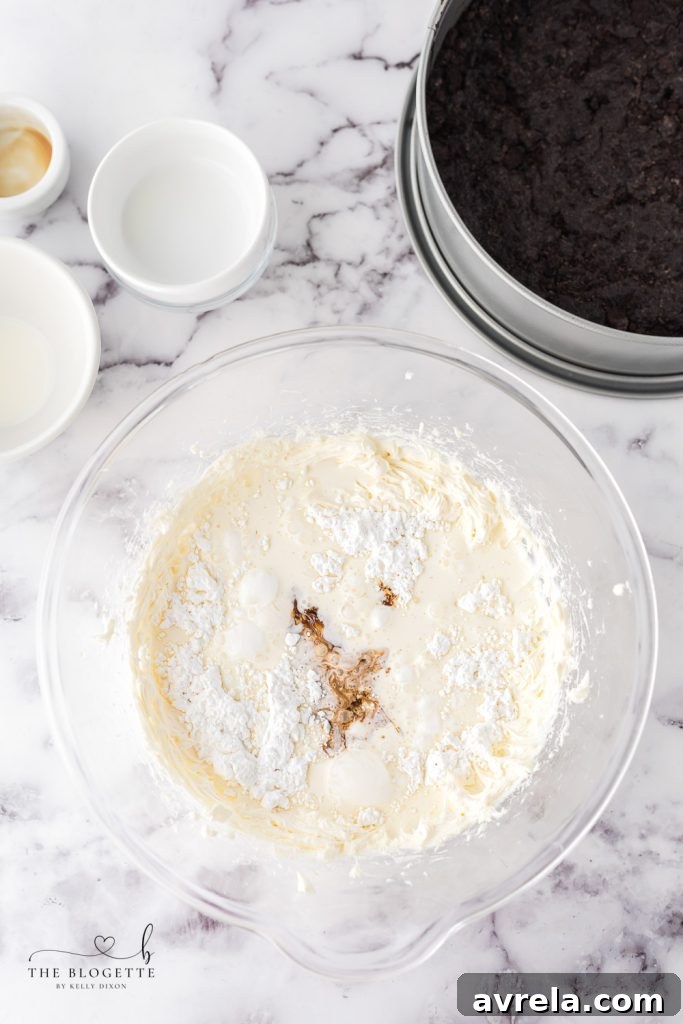 Oreo Dream Cheesecake 5 A large mixing bowl with smooth, whipped cream cheese, showcasing the preparation of the cheesecake filling.