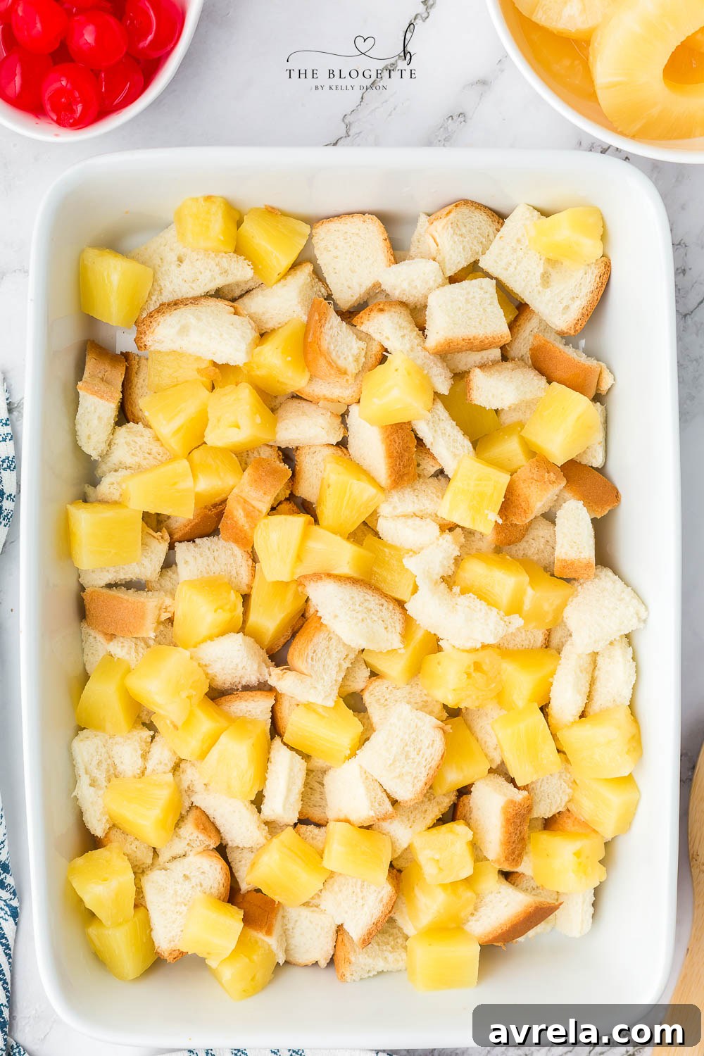 Pineapple chunks and bread cubes covered with egg mixture in a baking dish.