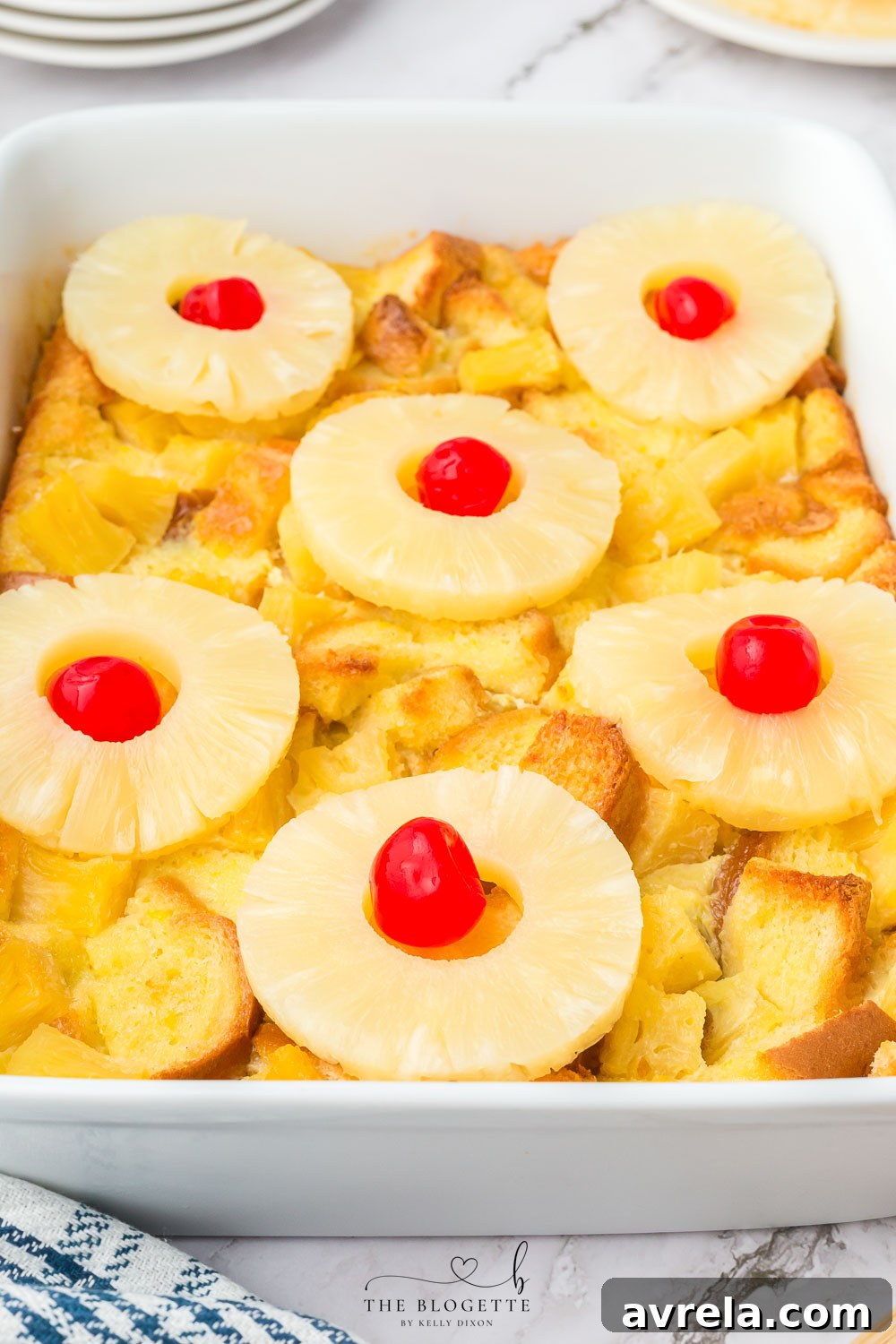 Fully baked Pineapple Casserole topped with pineapple rings and maraschino cherries.