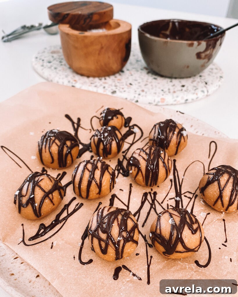A tray of partially assembled homemade peanut butter cups in their liners, with the peanut butter filling clearly visible over the hardened chocolate base, ready for the top layer.