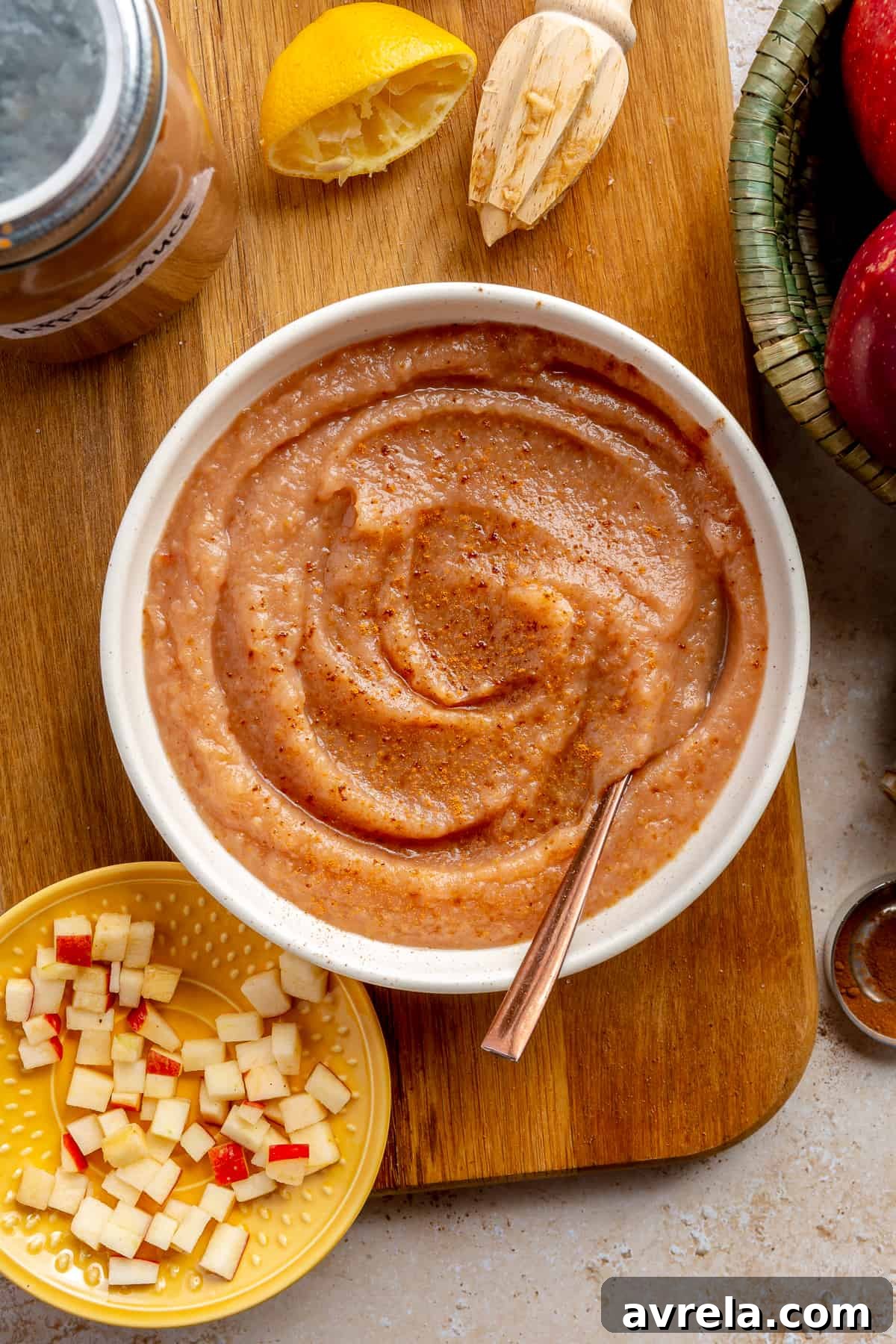 Delicious homemade cinnamon applesauce in a white bowl, garnished with cinnamon sticks and fresh apple slices.