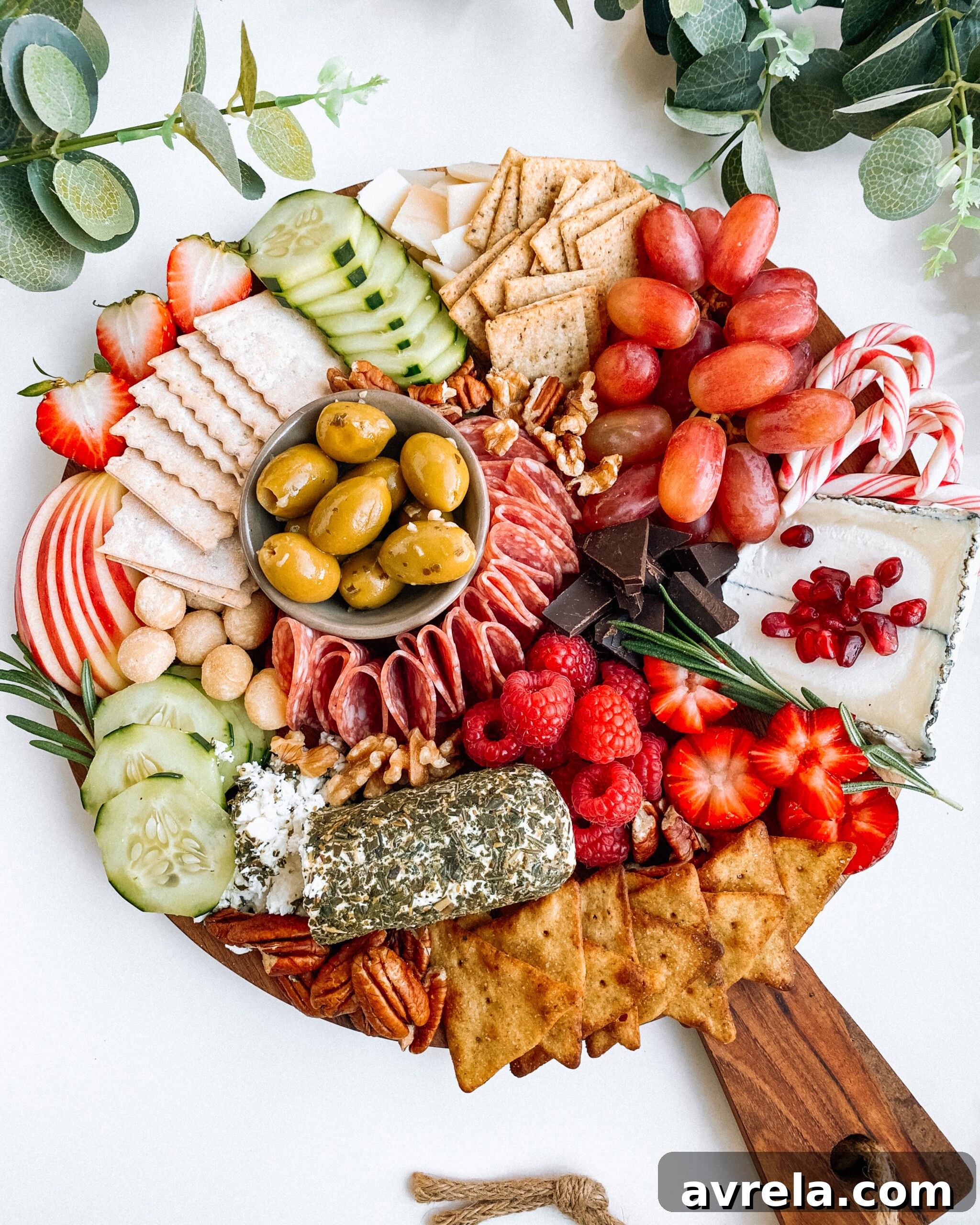 Vibrant Holiday Charcuterie Board brimming with festive red and green ingredients like berries, grapes, salami, and rosemary.