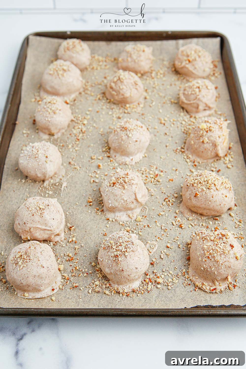 Dipped Apple Pie Truffles on a baking sheet, some with nuts sprinkled on top, waiting to set.