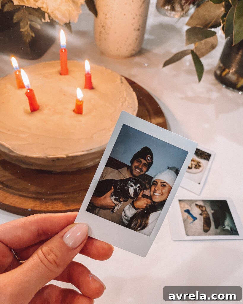 A person holding a small brown dachshund puppy with a birthday cake in front of them.