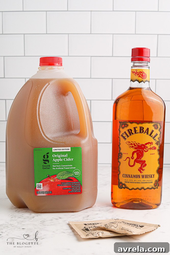 A selection of ingredients for making Apple Pie Jello Shots, including gelatin, apple cider, Fireball, and jello shot cups.