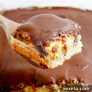 A vibrant image of the Boston Cream Poke Cake, featuring its golden cake base, creamy vanilla filling, and shiny chocolate top. This recipe is an easy twist on the classic Boston Cream Pie.