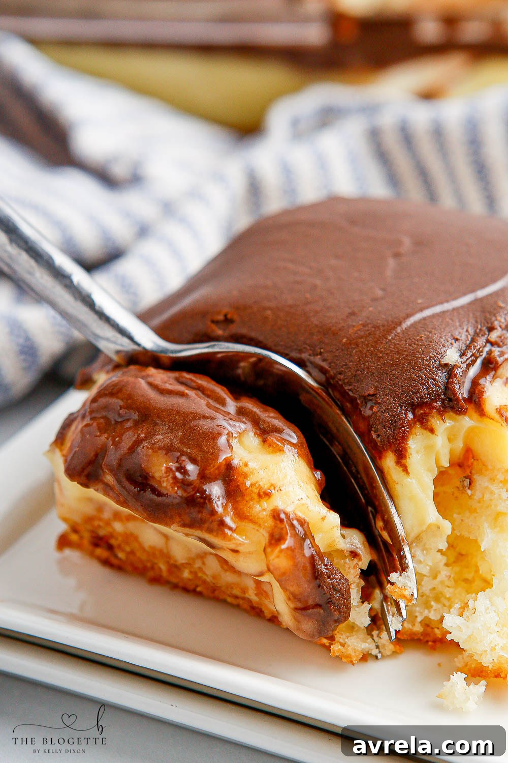 The second view of a prepared Boston Cream Poke Cake, highlighting its inviting layers of golden cake, creamy vanilla pudding, and shiny chocolate topping, beautifully arranged and ready to be served.