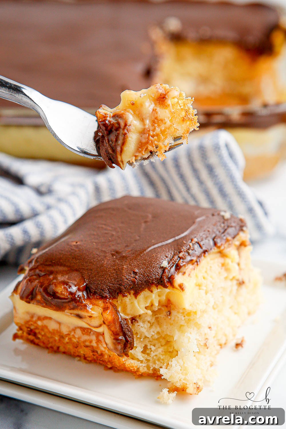 Another beautiful perspective of the finished Boston Cream Poke Cake, highlighting its moist cake, rich pudding, and shiny chocolate top, confirming its appealing texture and ease of preparation.