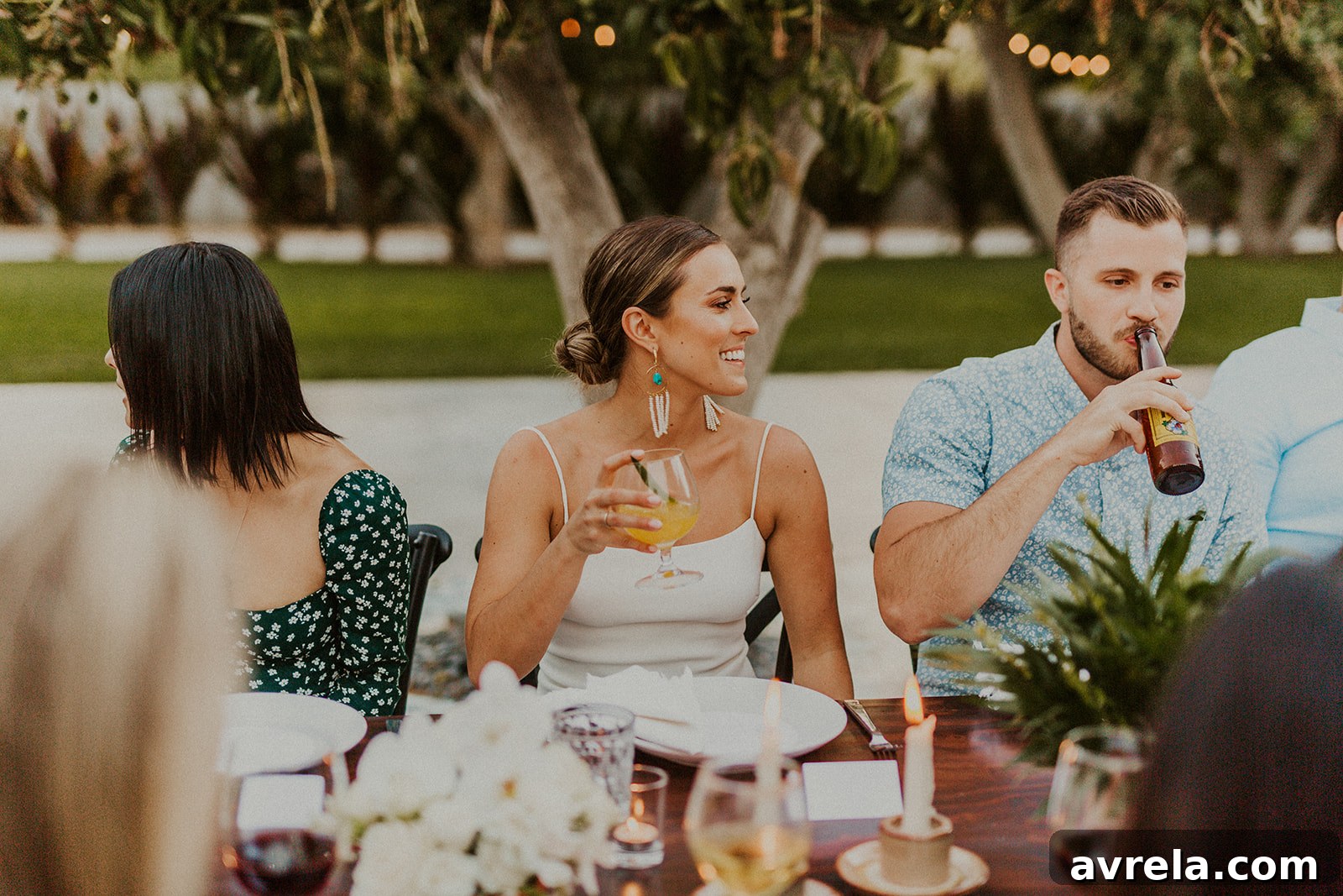 A candid moment of the bride and groom enjoying their rehearsal dinner with guests in the background