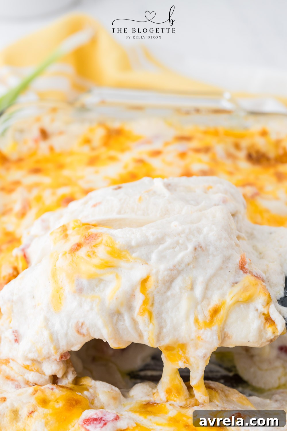 A baking dish filled with rolled creamy white chicken enchiladas, generously covered in sauce and cheese, ready for the oven.