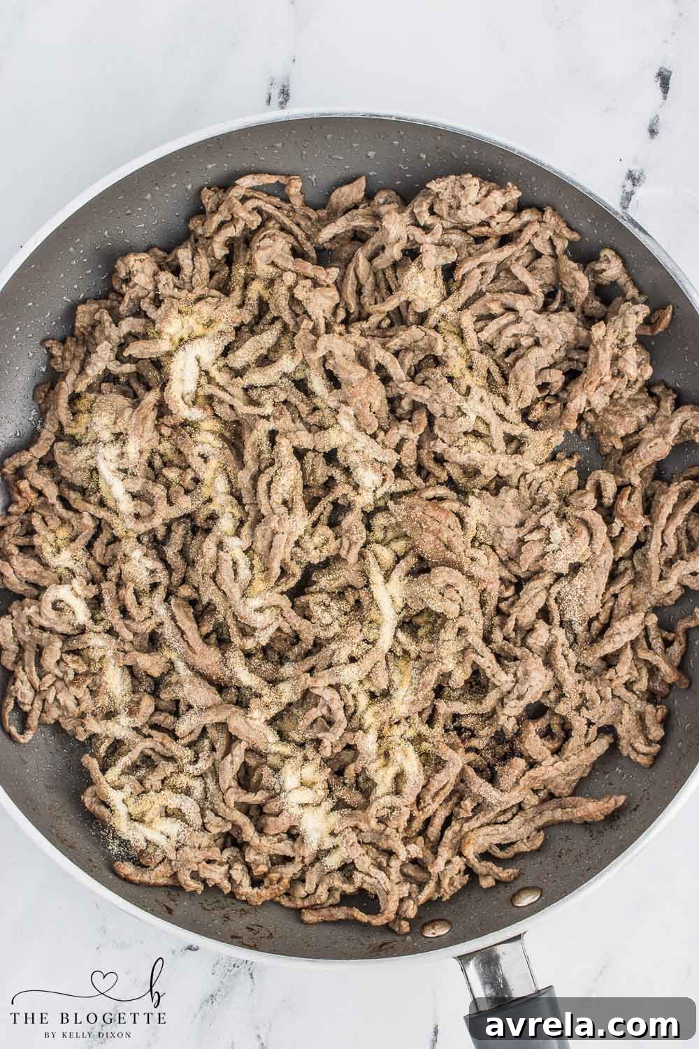 Philly Cheesesteak Comfort Bake 5 Thinly sliced steak seasoned with spices, browning in a large skillet, ready to be incorporated into the Philly Cheesesteak Casserole.