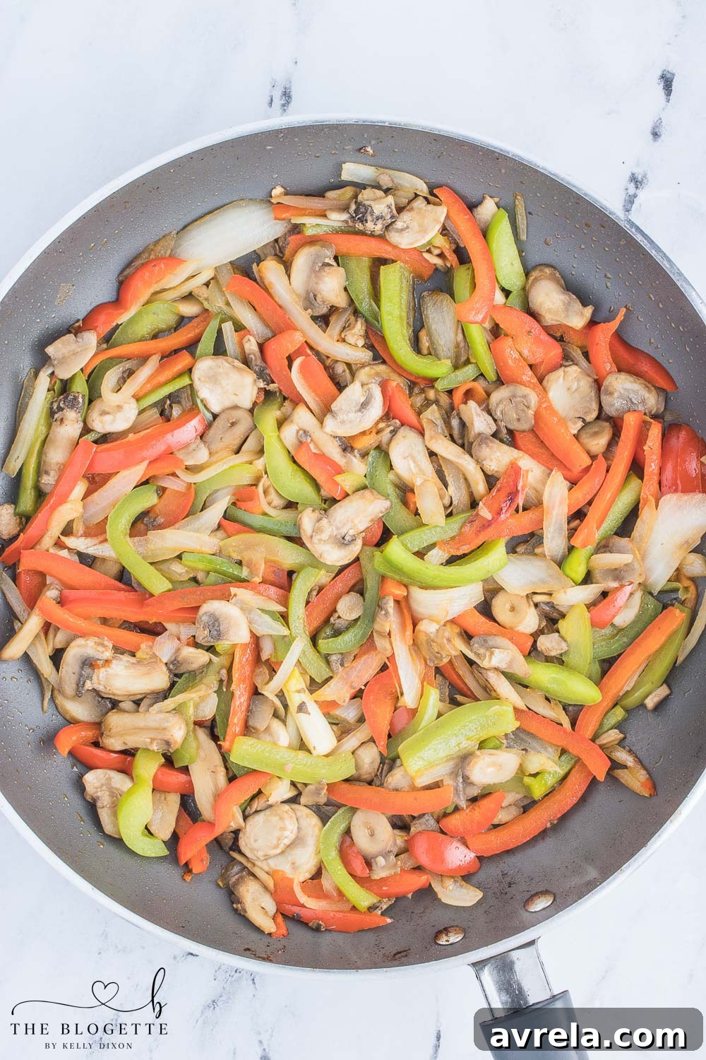 Philly Cheesesteak Comfort Bake 6 A mix of sautéed bell peppers, mushrooms, and onions in a skillet, tender and flavorful, forming the vegetable base for the cheesesteak mixture.