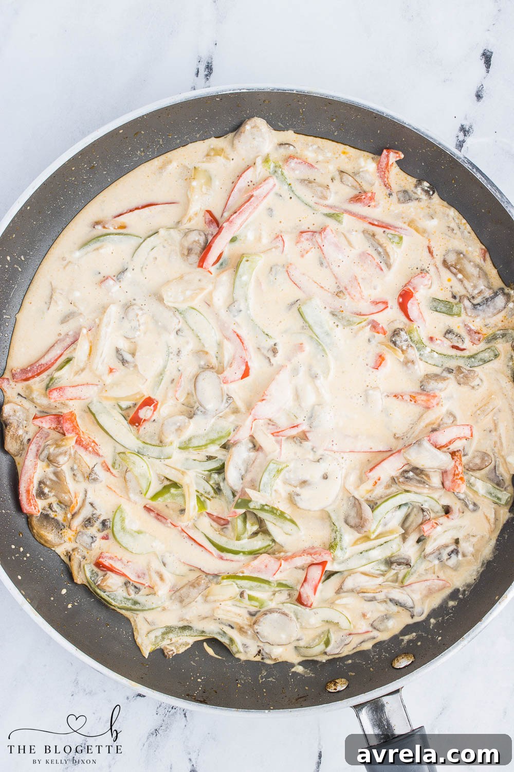 Philly Cheesesteak Comfort Bake 8 The creamy cheesesteak mixture fully combined in the skillet, with steak, vegetables, and sauce harmoniously blended, ready for the casserole dish.