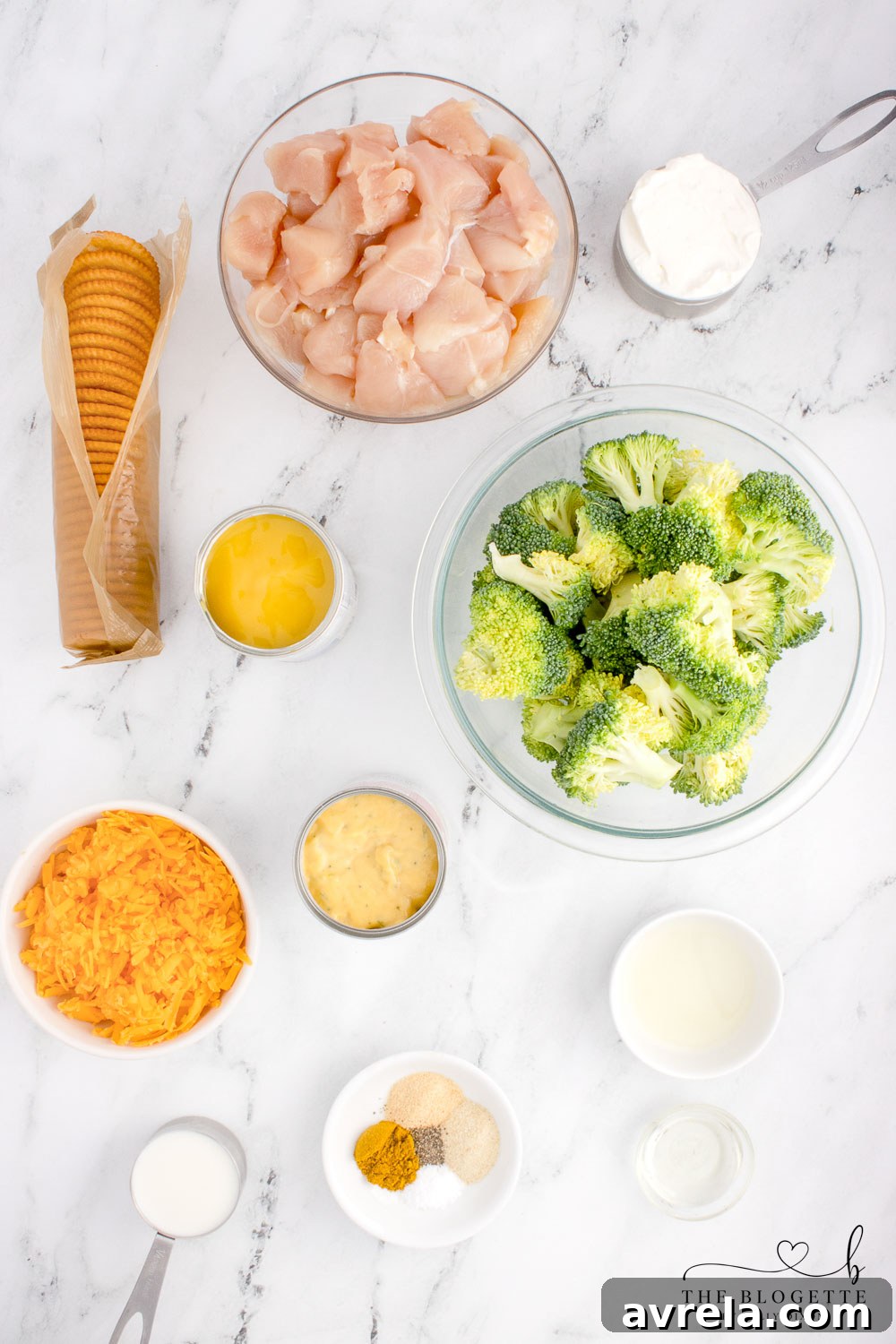 All the fresh ingredients laid out: chicken, broccoli, soups, sour cream, milk, lemon, cheese, and crackers, ready for Chicken Divan preparation.