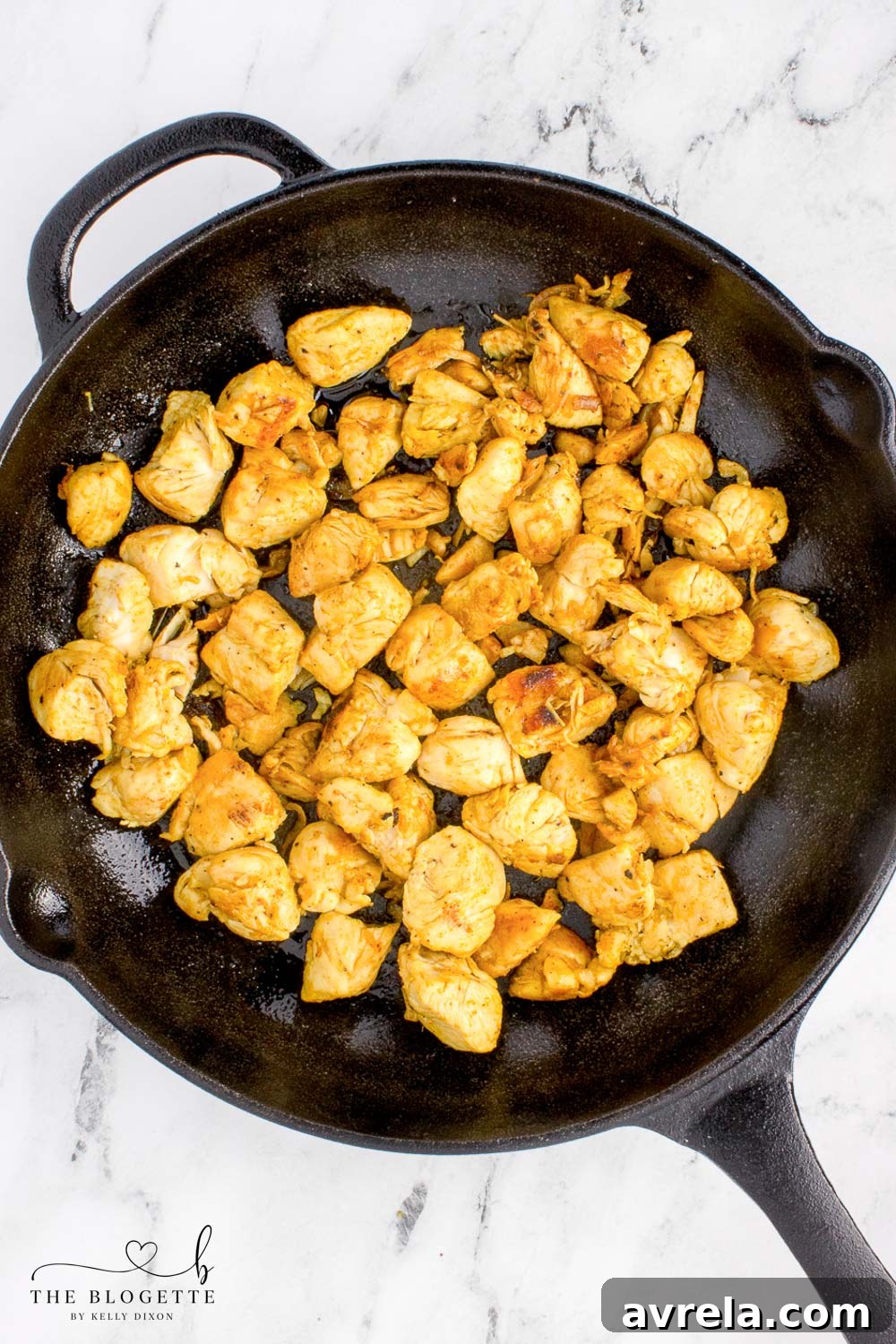 Cooked, seasoned chicken cubes in a skillet, slightly browned and ready to be added to the creamy casserole mixture.