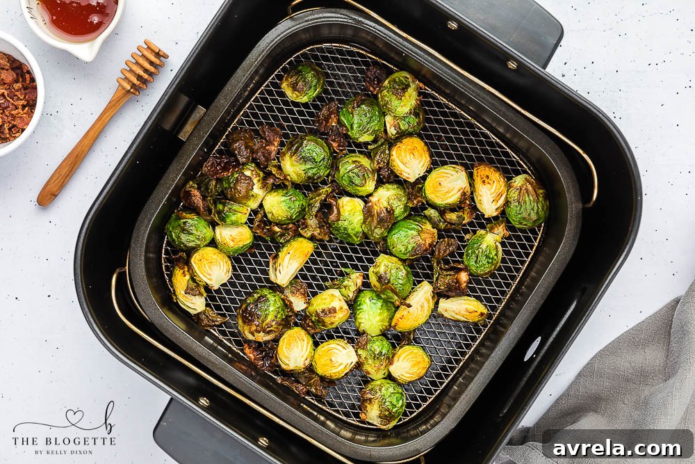 Air fryer basket filled with Honey Bacon Brussels Sprouts, showing even browning.