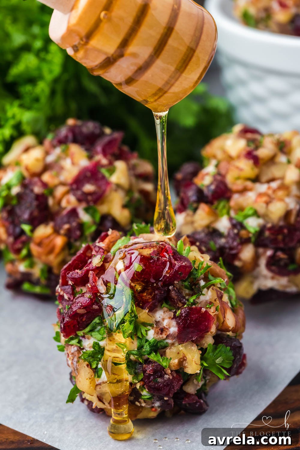 A close-up of a Cranberry Pecan Goat Cheese Ball, showcasing its vibrant red and green coating against the creamy white cheese interior.