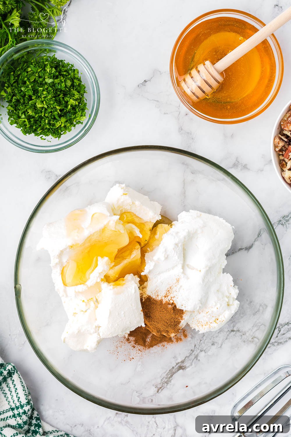 A vibrant display of fresh ingredients: creamy goat cheese, cream cheese, cinnamon, honey, pecans, parsley, dried cranberries, and salt, laid out for the recipe.