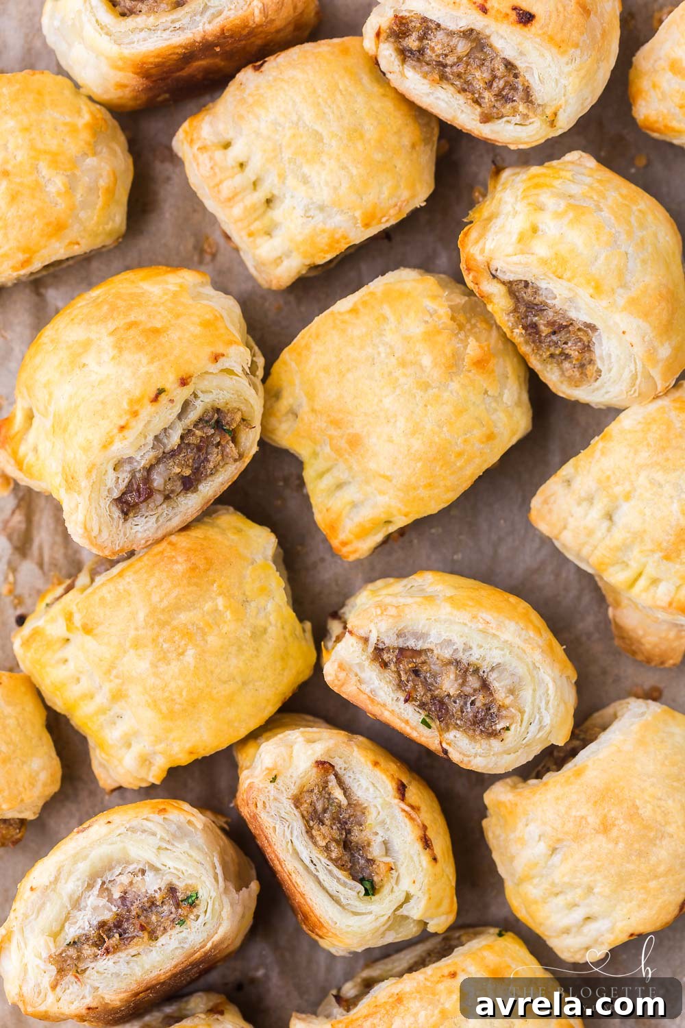 Close-up of golden puff pastry sausage rolls on a white platter, highlighting their perfect texture.